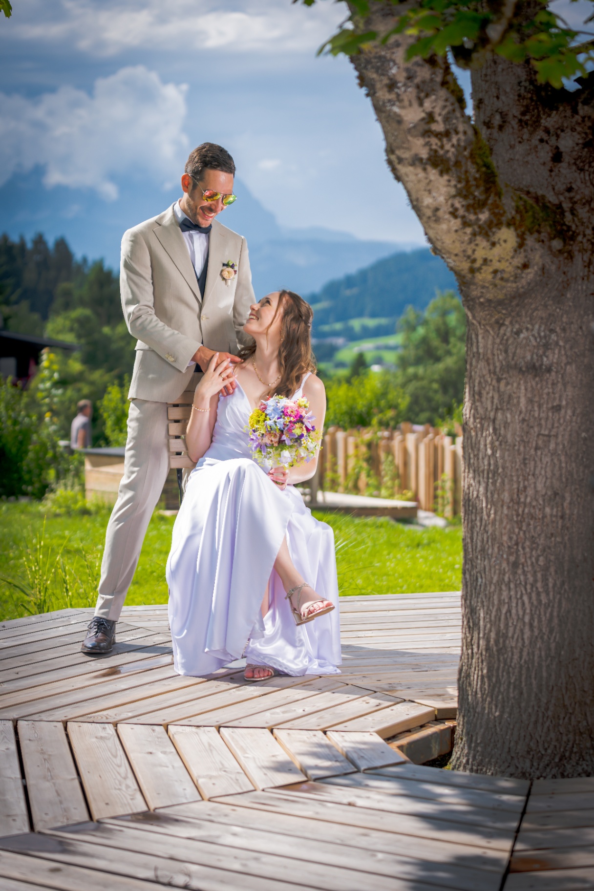 Braut sitzt lachend, Daniel mit Sonnenbrille daneben